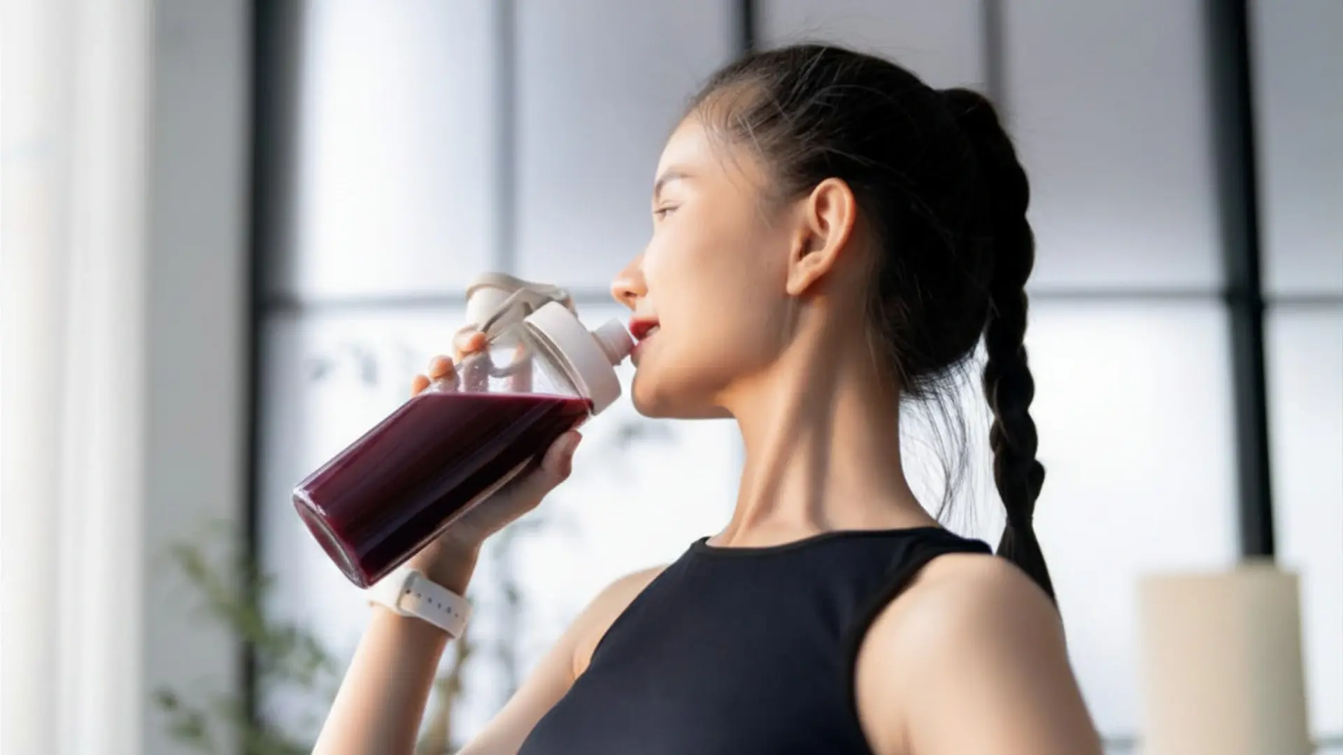 Woman drinking a deep violet functional beverage made with Maqui Berry anthocyanin concentrate during a workout
